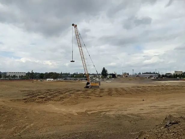 single-crane-dynamic-compaction-site-densification Liebherr crane performing dynamic compaction at a construction site in Oregon, with impact zones visible on the compacted soil surface.