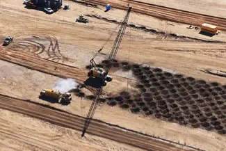 High-Impact Ground Improvement at Scale Aerial view of a crane performing dynamic compaction across a large grid pattern with visible impact craters on a construction site.